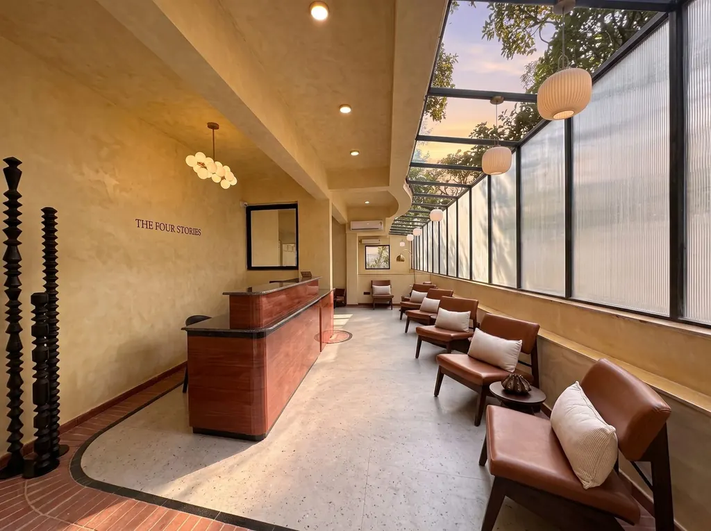 Lobby of The Four Stories, Udaipur: glass roof, warm textured walls, leather chairs and the front desk beneath the hotel name