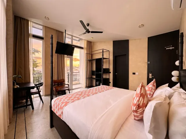 Superior Room with Balcony: four-poster bed, writing desk and glass doors to a balcony at sunset over Udaipur